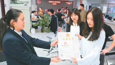 河北省承德市網(wǎng)絡(luò)代購經(jīng)營者陳晨(右)從工作人員手中接過帶有統(tǒng)一社會信用代碼的營業(yè)執(zhí)照。 劉環(huán)宇攝(人民圖片)