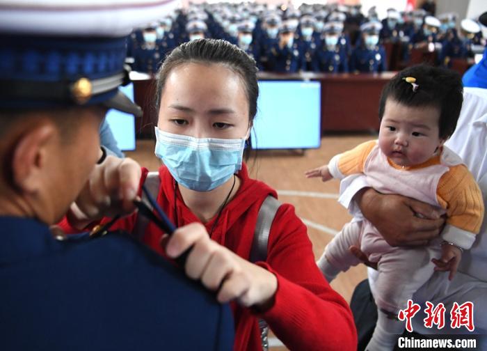 新消防員楊振的妻子彭莉與女兒現(xiàn)場見證丈夫加入“火焰藍”的神圣時刻?！⒅铱?攝