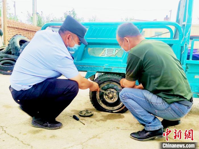 賽旦與民警共同維修三輪摩托車。　依力哈木江 攝