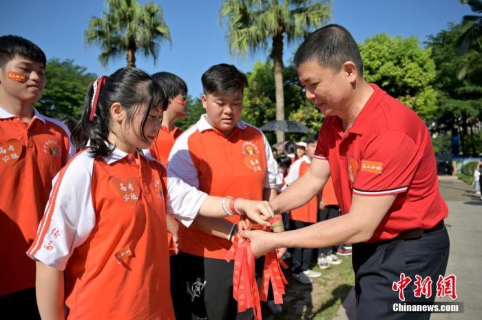 資料圖：廣西華僑實(shí)驗(yàn)高中的教師為高三學(xué)子系上紅絲帶，盼望學(xué)子高考必勝。 俞靖 攝